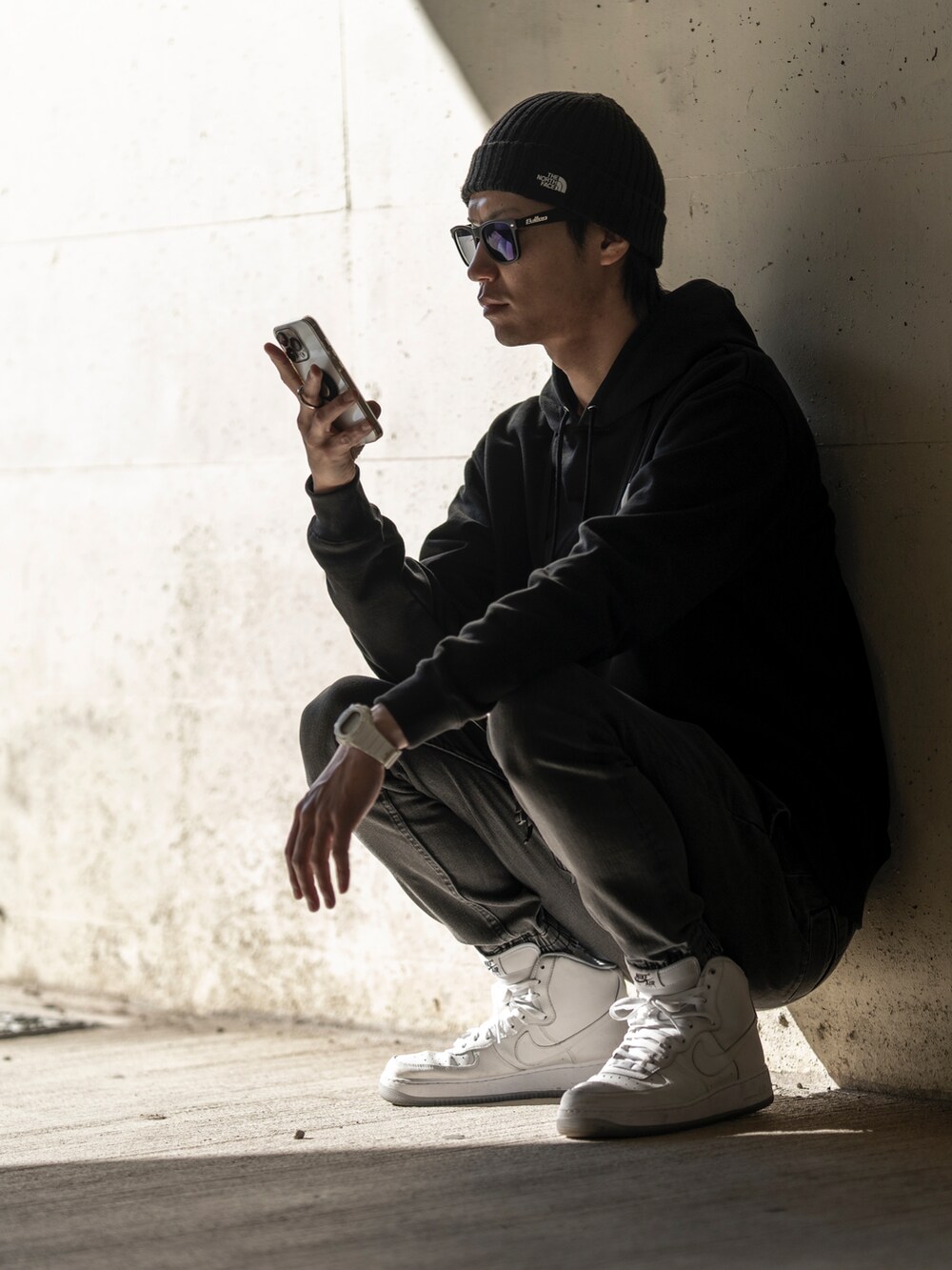 ブラック系のパーカー、ブラック系のショルダーバッグ、ブラック系のデニムパンツを着用したメンズの冬コーディネートの2枚目の写真