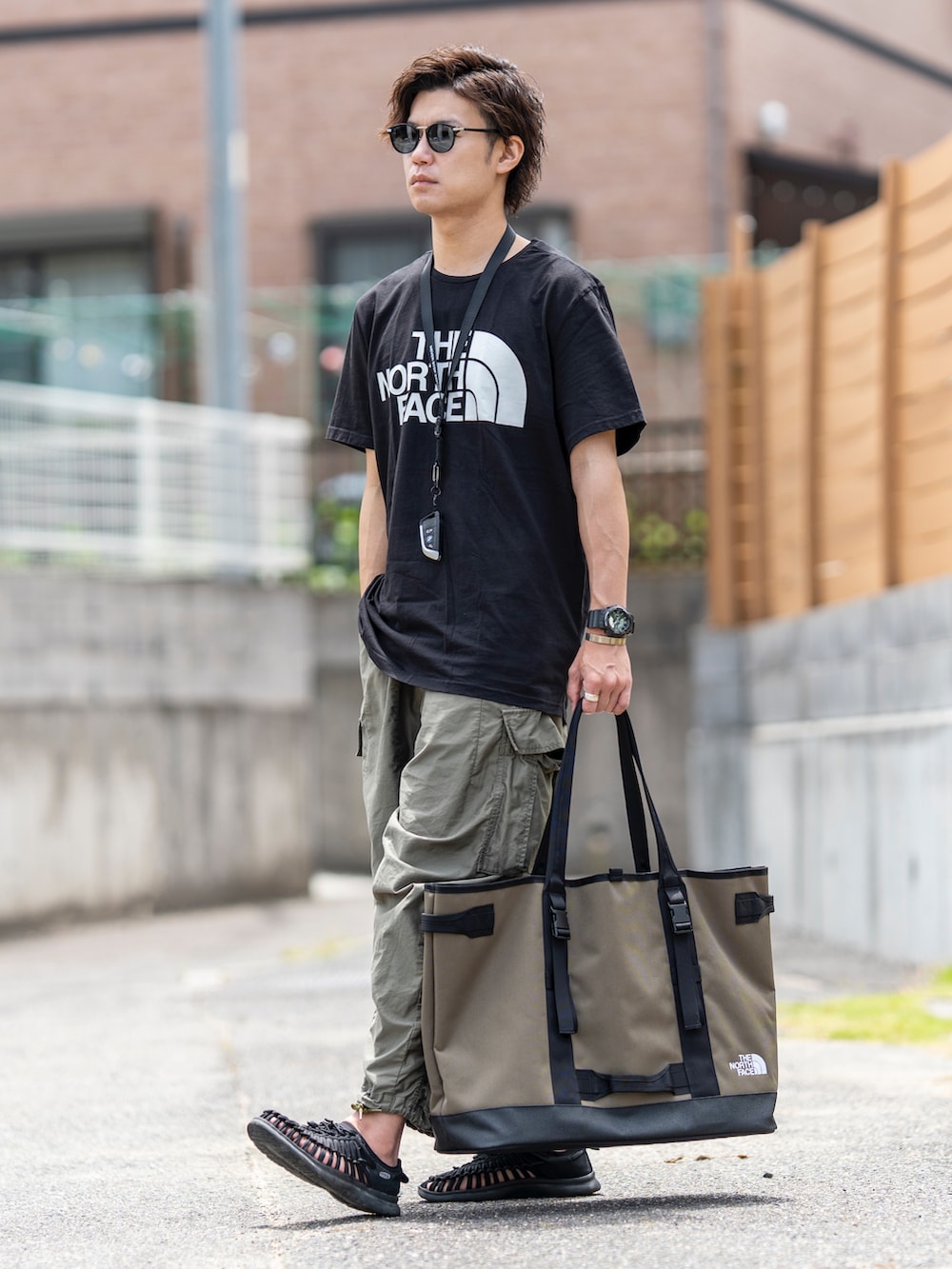 ブラック系のTシャツ/カットソー、グリーン系のトートバッグ、グリーン系のカーゴパンツを着用したメンズの夏コーディネートの3枚目の写真