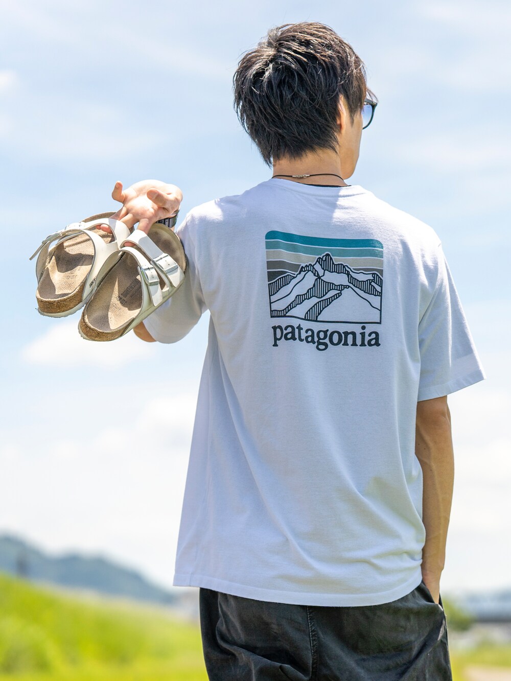 ホワイト系のTシャツ/カットソー、ブラック系のその他パンツ、ブラック系のサンダルを着用したメンズの夏コーディネートの2枚目の写真