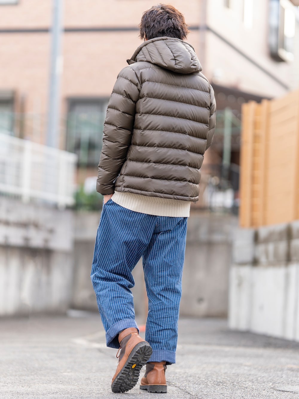 ブラウン系のダウンジャケット/コート、ホワイト系のニット/セーター、ブルー系のパンツを着用したメンズの冬コーディネートの2枚目の写真