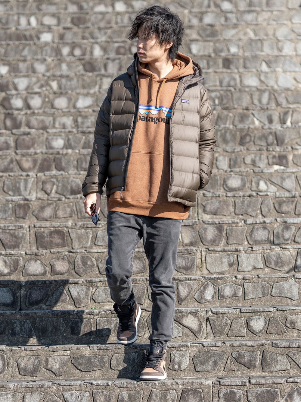 ブラウン系のパーカー、ブラウン系のダウンジャケット/コート、ブラック系のデニムパンツを着用したメンズの冬コーディネートの2枚目の写真
