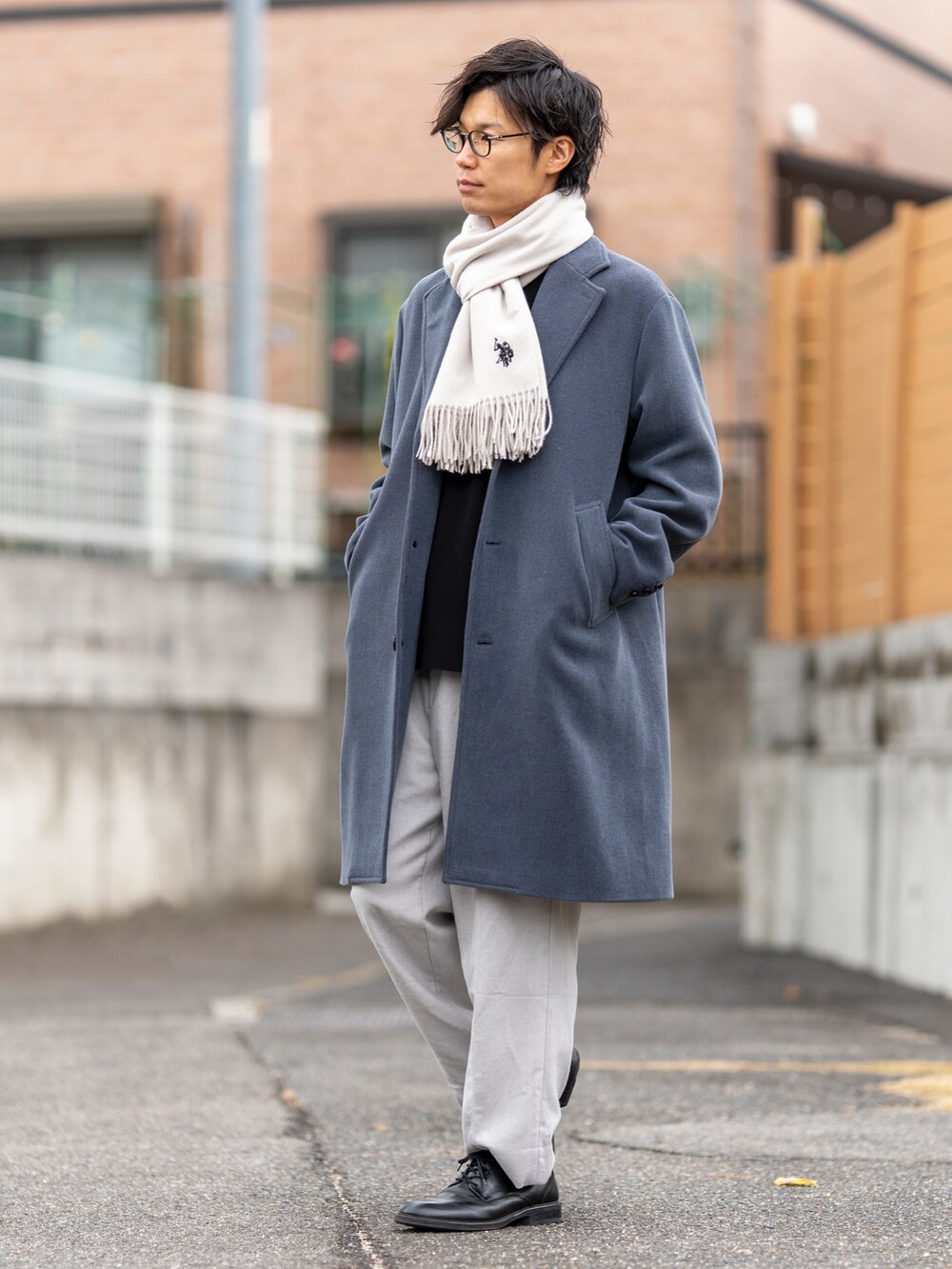 ブルー系のチェスターコート、ブラック系のニット/セーター、ブラック系のシューズを着用したメンズの冬コーディネートの3枚目の写真