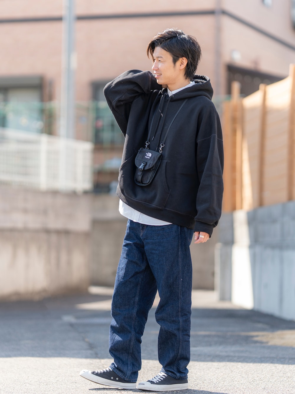 ブラック系のパーカー、ホワイト系のトップス、ブルー系のデニムパンツを着用したメンズの春コーディネートの2枚目の写真