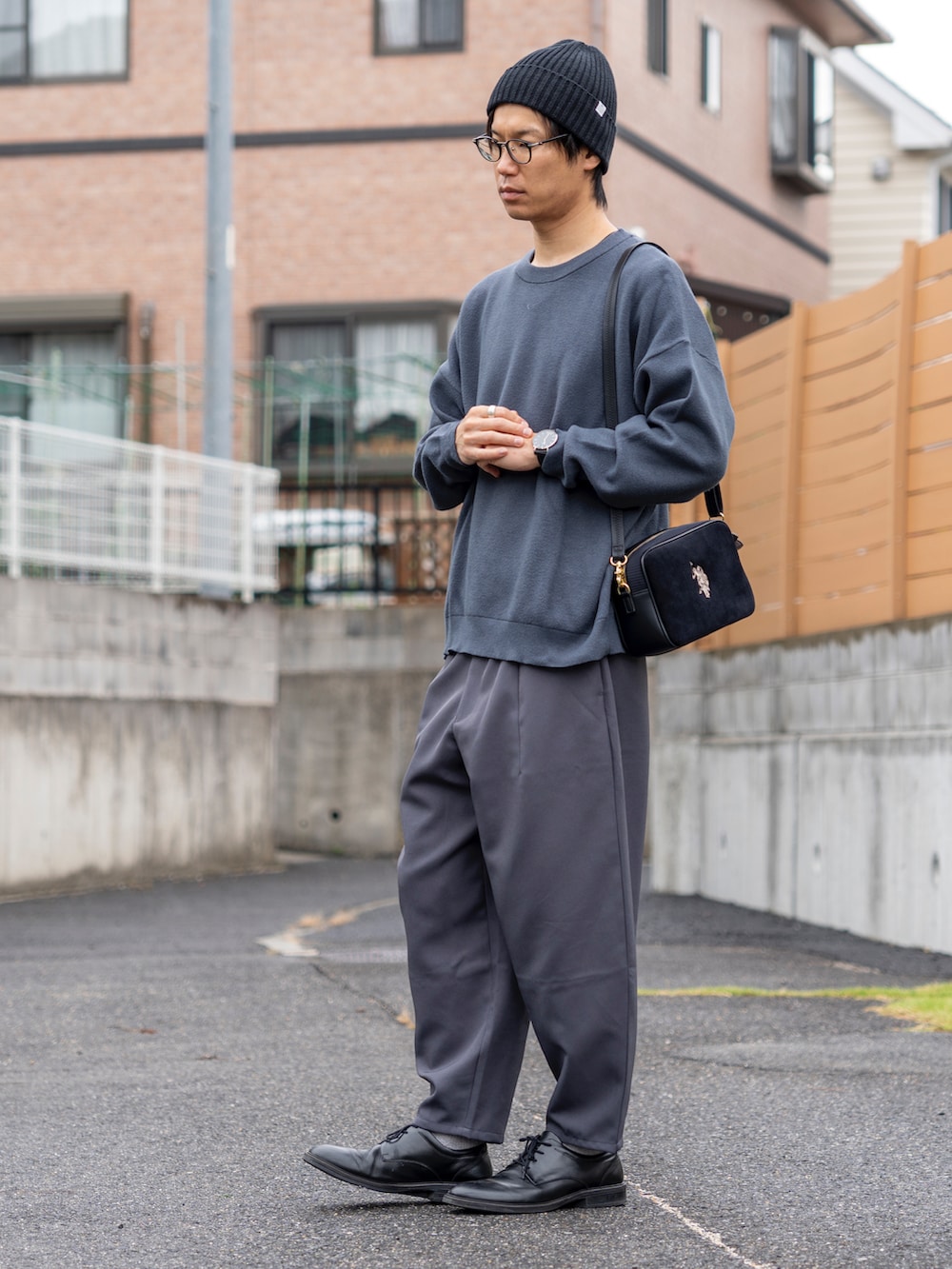 ブルー系のトップス、ブラック系のショルダーバッグ、グレー系のパンツを着用したメンズの秋コーディネートの4枚目の写真