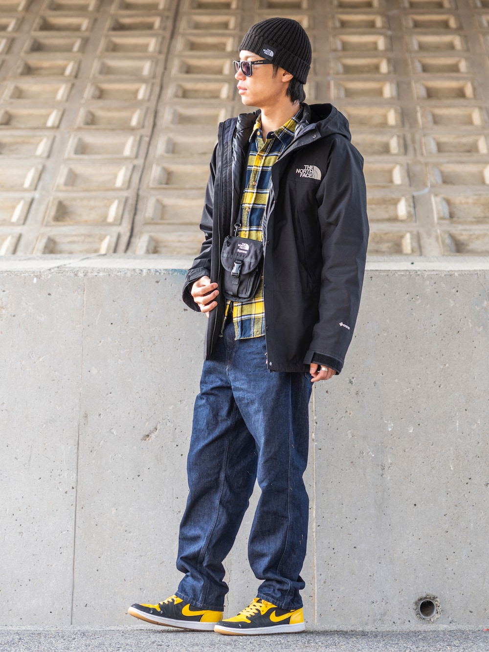 ブラック系のマウンテンパーカー、ブラック系のダウンジャケット/コート、イエロー系のシャツ/ブラウスを着用したメンズの冬コーディネートの2枚目の写真