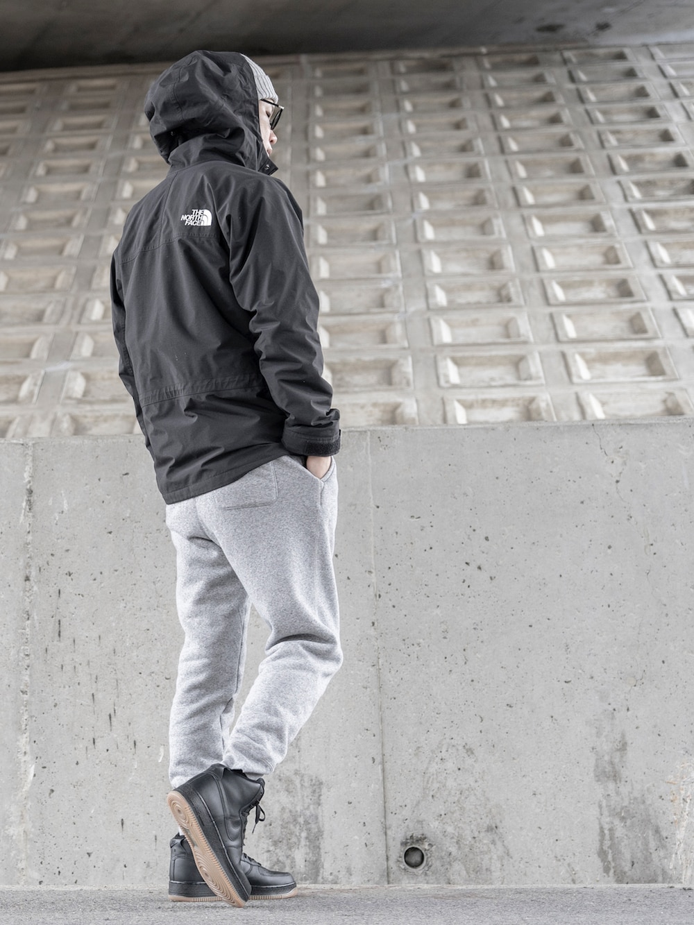 ブラック系のマウンテンパーカー、グレー系のその他パンツ、ブラック系のスニーカーを着用したメンズの冬コーディネートの2枚目の写真