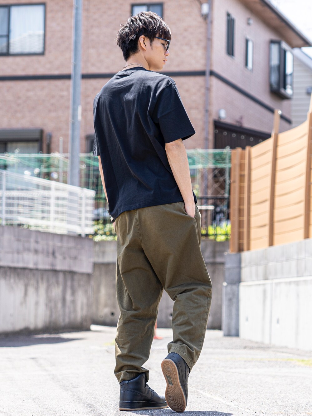 ブラック系のTシャツ/カットソー、グリーン系のチノパンツ、ブラック系のスニーカーを着用したメンズの夏コーディネートの2枚目の写真