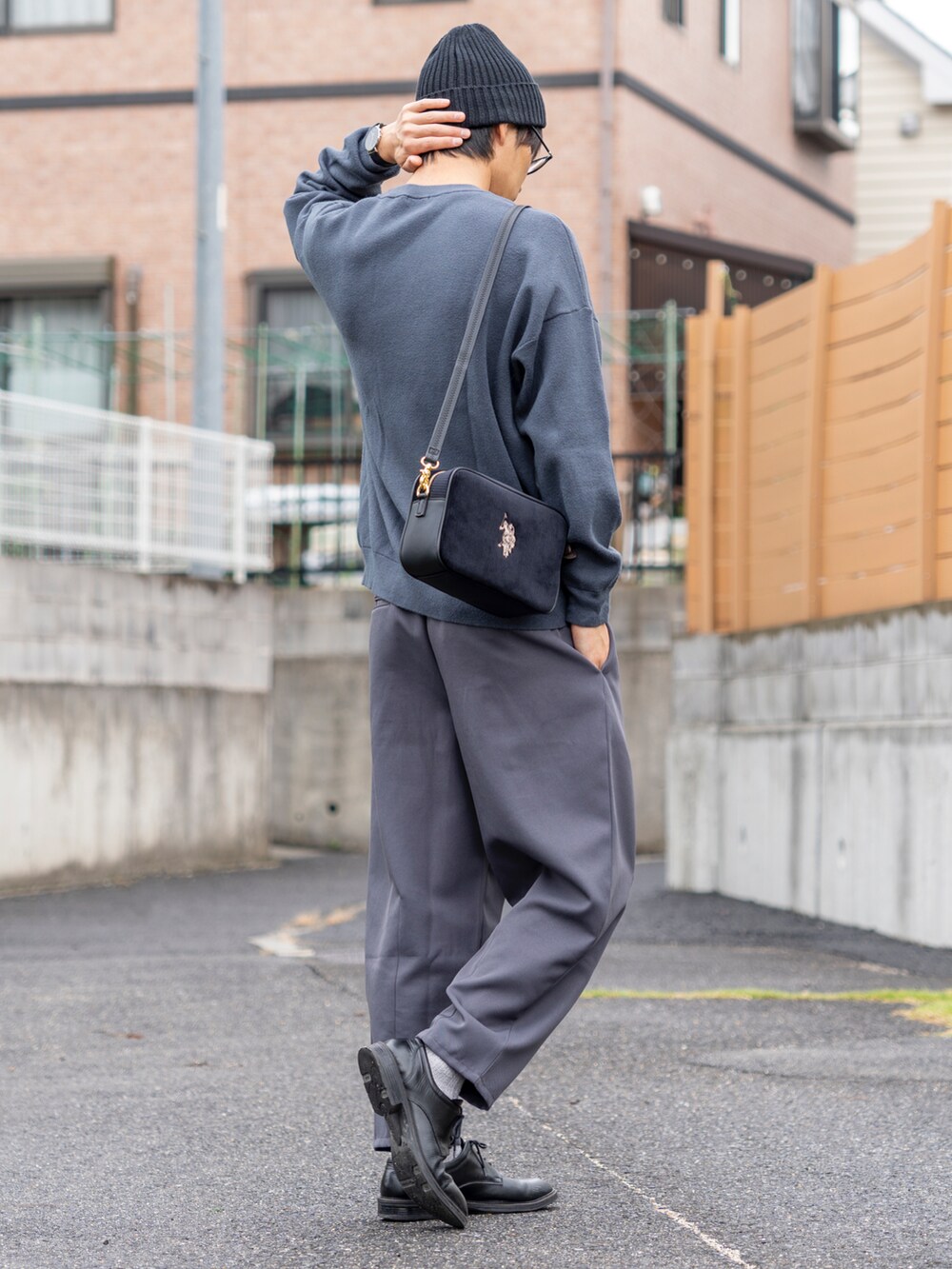 ブルー系のトップス、ブラック系のショルダーバッグ、グレー系のパンツを着用したメンズの秋コーディネートの3枚目の写真