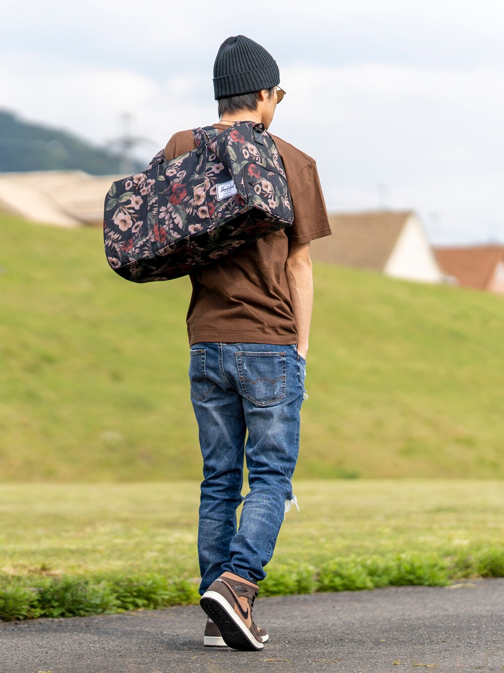 ブラウン系のTシャツ/カットソー、ブルー系のデニムパンツ、その他のボストンバッグを着用したメンズの春コーディネートの2枚目の写真