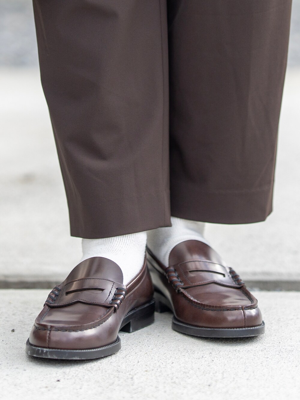 ベージュ系のステンカラーコート、ホワイト系のTシャツ/カットソー、ブラウン系のニット/セーターを着用したメンズの冬コーディネートの3枚目の写真