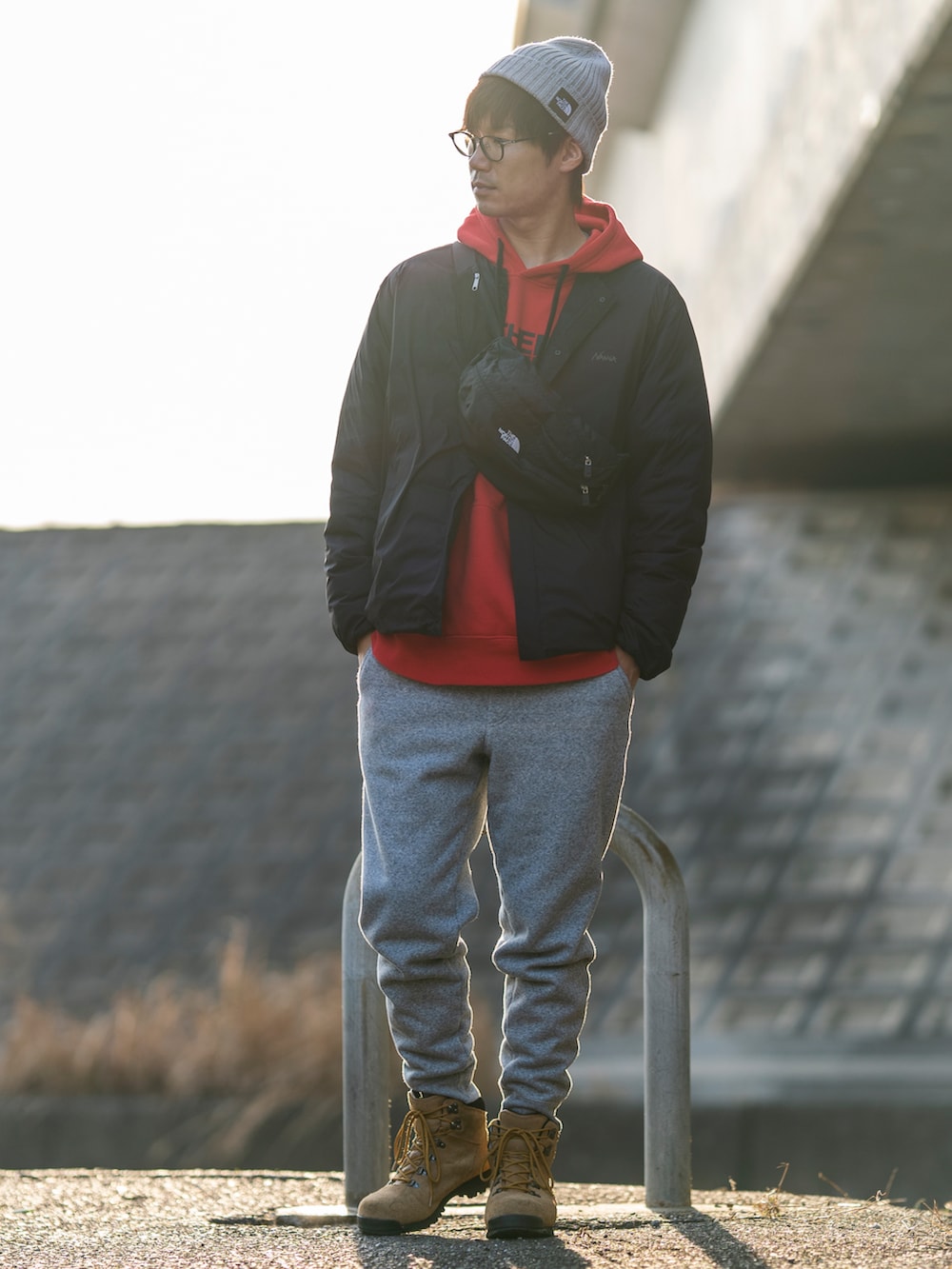 ブラック系のダウンジャケット/コート、レッド系のパーカー、ブラック系のボディバッグ/ウエストポーチを着用したメンズの冬コーディネートの2枚目の写真