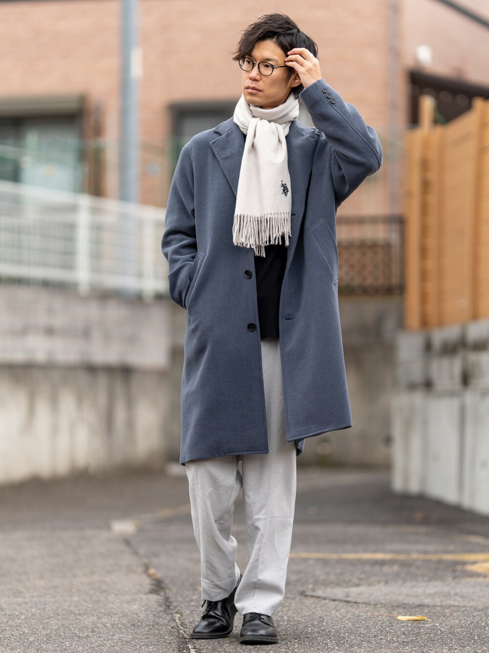 ブルー系のチェスターコート、ブラック系のニット/セーター、ブラック系のシューズを着用したメンズの冬コーディネートの2枚目の写真
