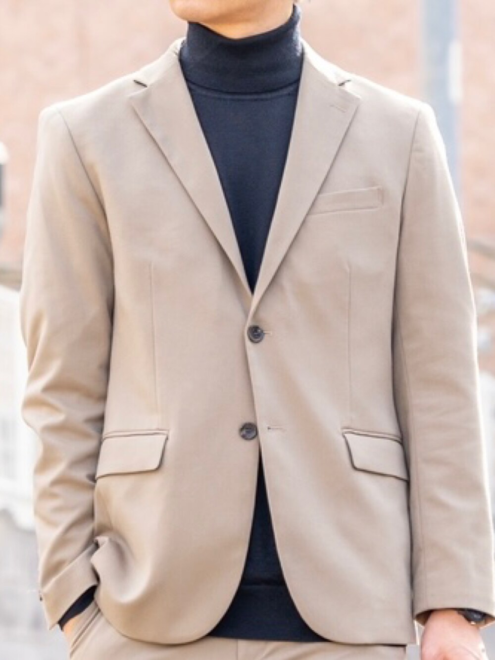 ベージュ系のテーラードジャケット、ブラック系のニット/セーター、ベージュ系のスラックスを着用したメンズの冬コーディネートの4枚目の写真