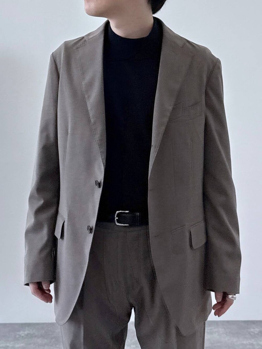 ブラウン系のテーラードジャケット、ブラウン系のスラックス、ブラック系のニット/セーターを着用したメンズの秋コーディネートの4枚目の写真