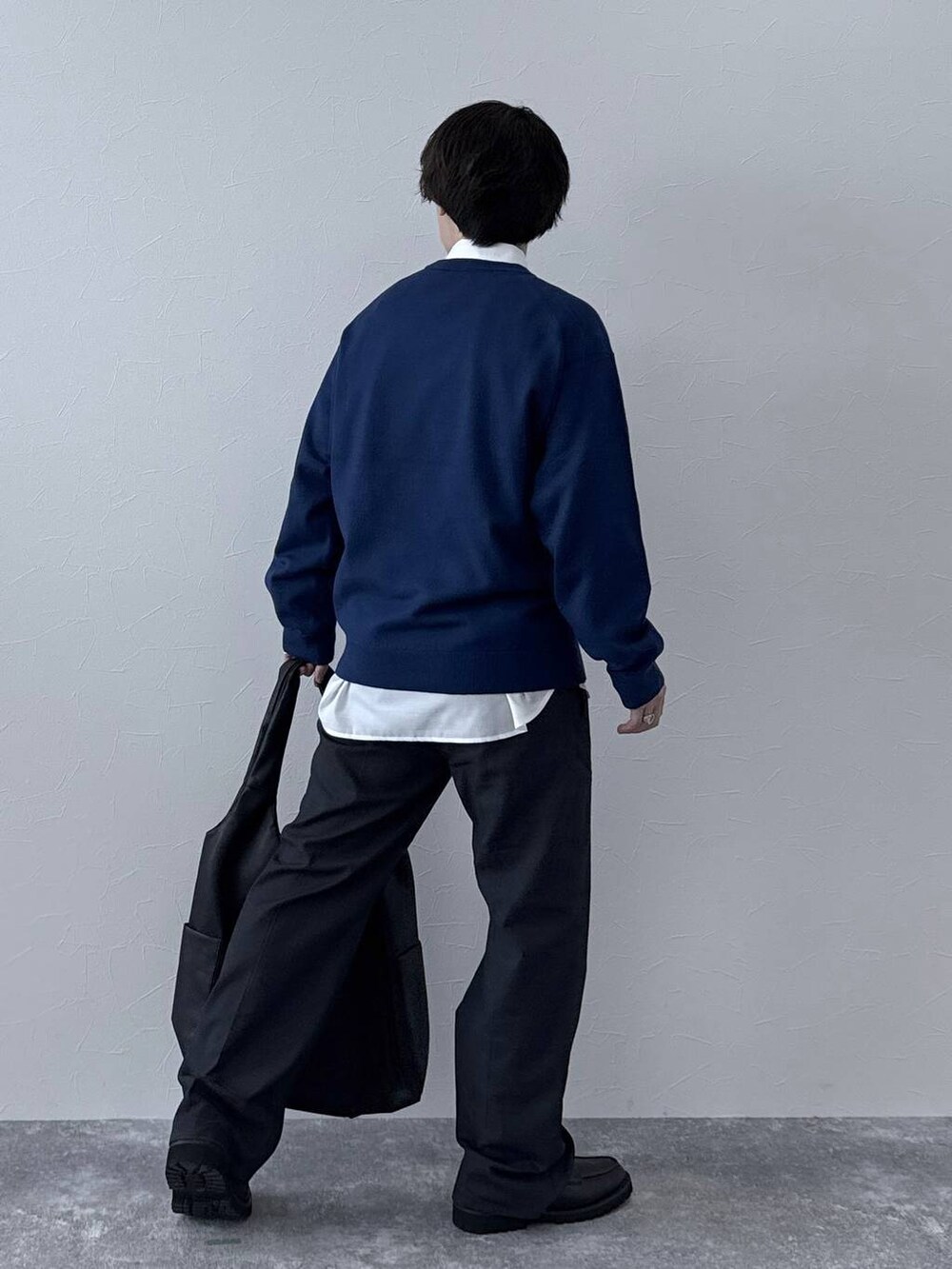 ブラック系のトートバッグ、ブラック系のその他シューズ、ブルー系のデニムパンツを着用したメンズの秋コーディネートの3枚目の写真