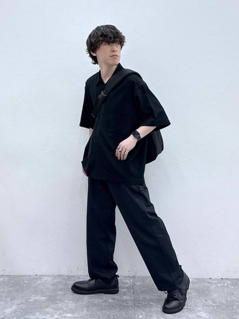 ブラック系のメッセンジャーバッグ、ブラック系のシャツ/ブラウス、ブルー系のデニムパンツを着用したメンズの春コーディネートの2枚目の写真