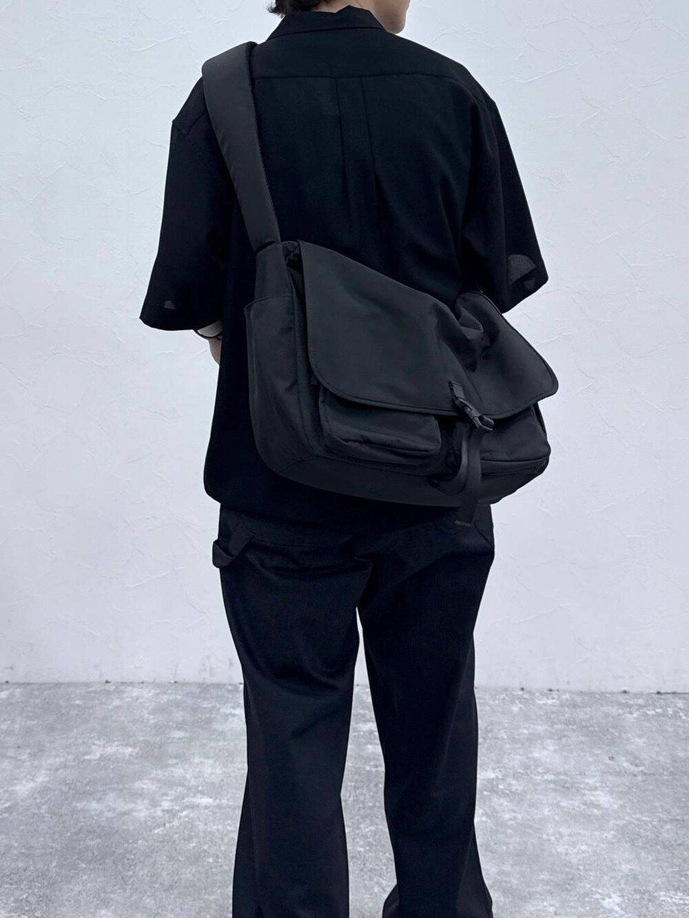 ブラック系のメッセンジャーバッグ、ブラック系のシャツ/ブラウス、ブルー系のデニムパンツを着用したメンズの春コーディネートの6枚目の写真