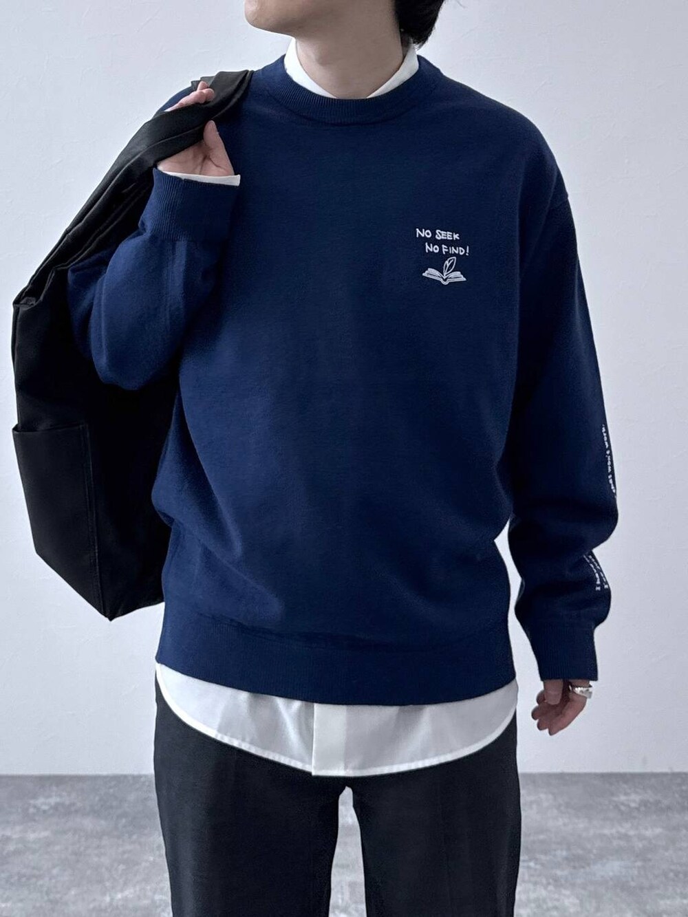 ブラック系のトートバッグ、ブラック系のその他シューズ、ブルー系のデニムパンツを着用したメンズの秋コーディネートの4枚目の写真