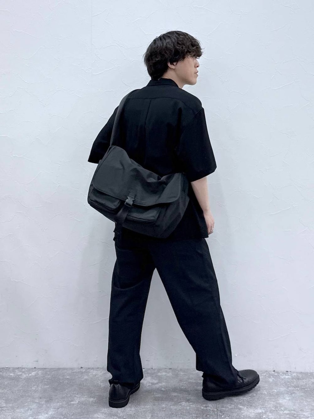ブラック系のメッセンジャーバッグ、ブラック系のシャツ/ブラウス、ブルー系のデニムパンツを着用したメンズの春コーディネートの3枚目の写真