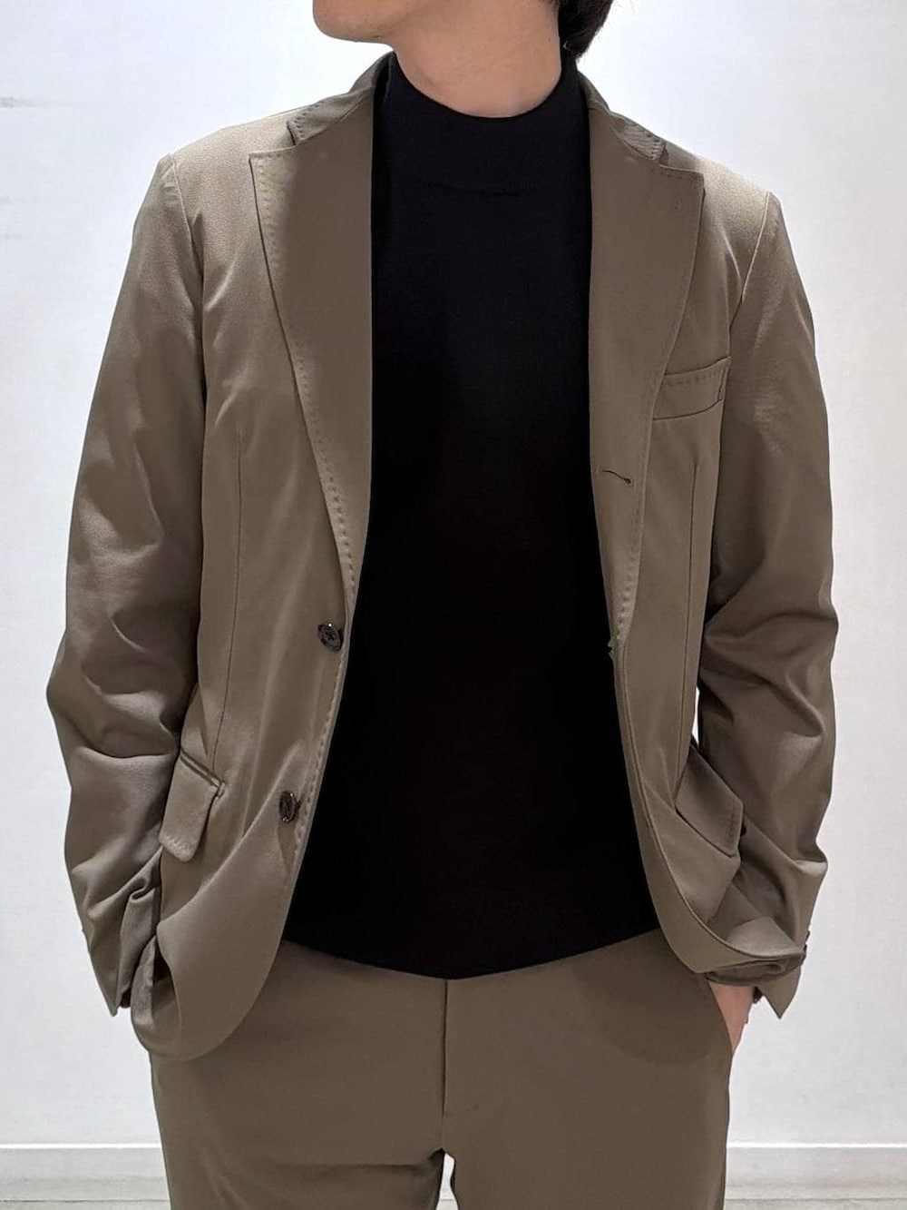 ブラック系のニット/セーター、ベージュ系のテーラードジャケット、ベージュ系のスラックスを着用したメンズの冬コーディネートの4枚目の写真