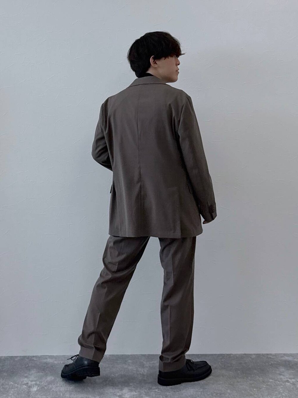 ブラウン系のテーラードジャケット、ブラウン系のスラックス、ブラック系のニット/セーターを着用したメンズの秋コーディネートの3枚目の写真