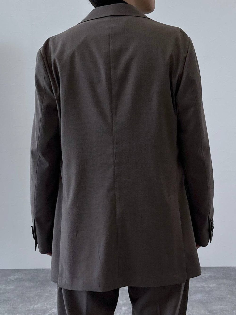 ブラウン系のテーラードジャケット、ブラウン系のスラックス、ブラック系のニット/セーターを着用したメンズの秋コーディネートの5枚目の写真