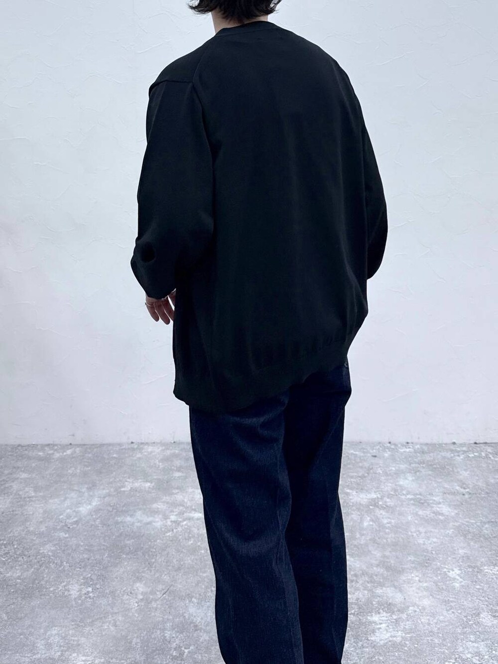 ブラック系のスニーカー、ブルー系のデニムパンツ、ブラック系のニット/セーターを着用したメンズの春コーディネートの5枚目の写真
