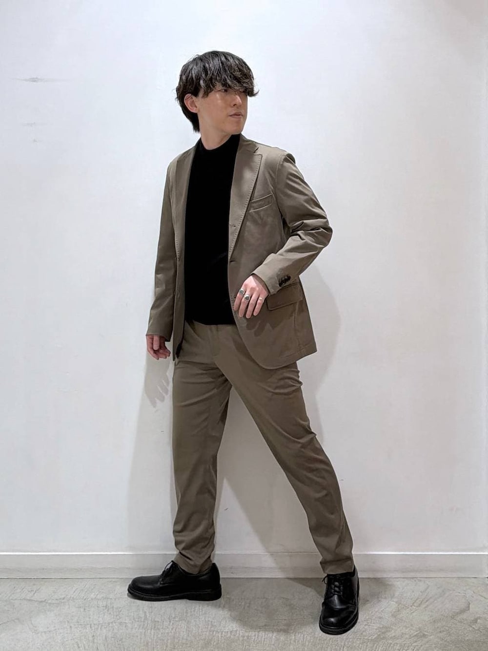 ブラック系のニット/セーター、ベージュ系のテーラードジャケット、ベージュ系のスラックスを着用したメンズの冬コーディネートの2枚目の写真