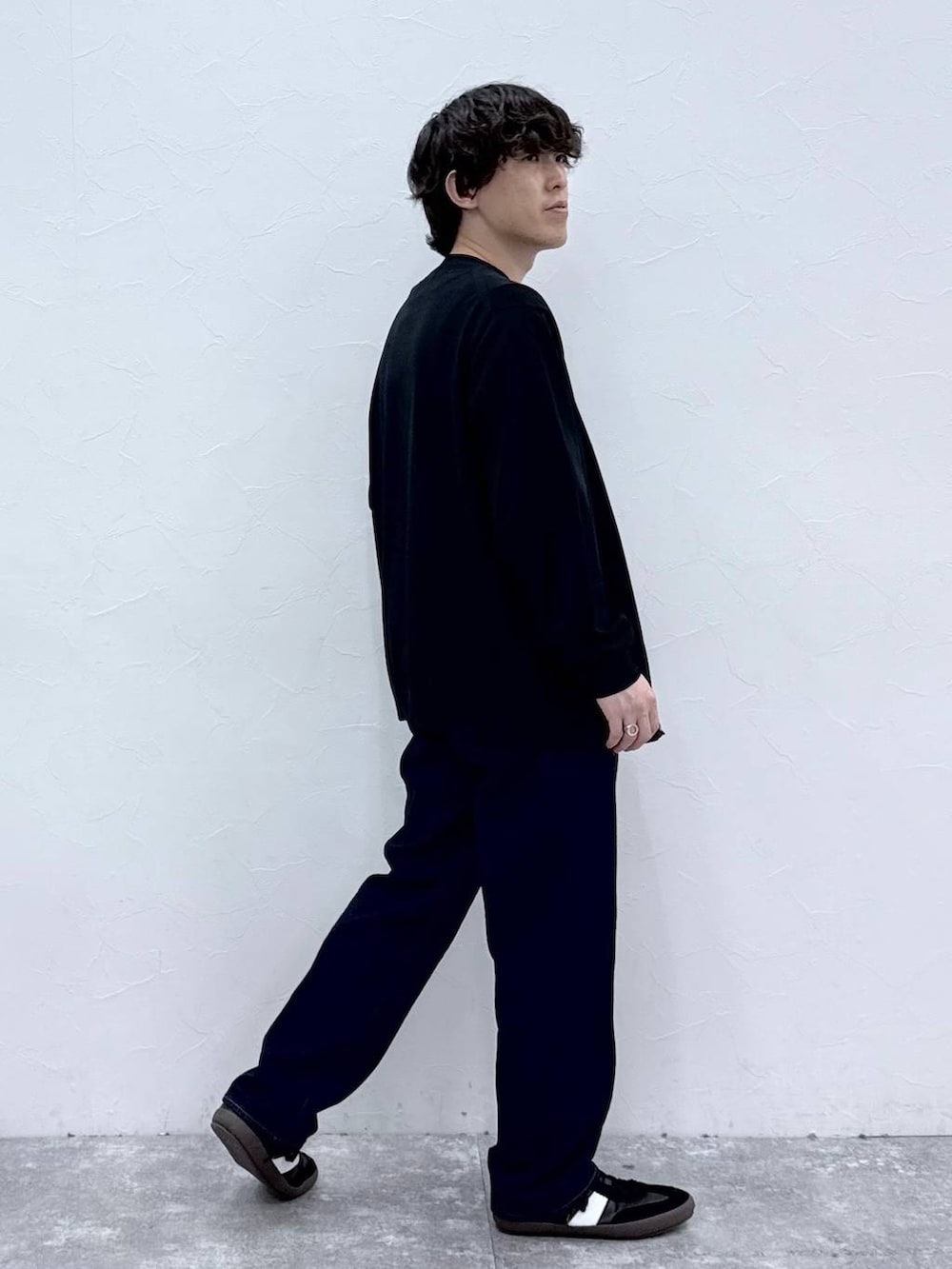 ブラック系のスニーカー、ブルー系のデニムパンツ、ブラック系のニット/セーターを着用したメンズの春コーディネートの3枚目の写真
