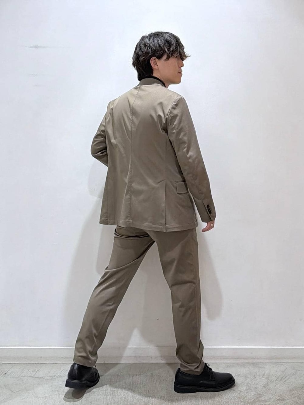 ブラック系のニット/セーター、ベージュ系のテーラードジャケット、ベージュ系のスラックスを着用したメンズの冬コーディネートの3枚目の写真