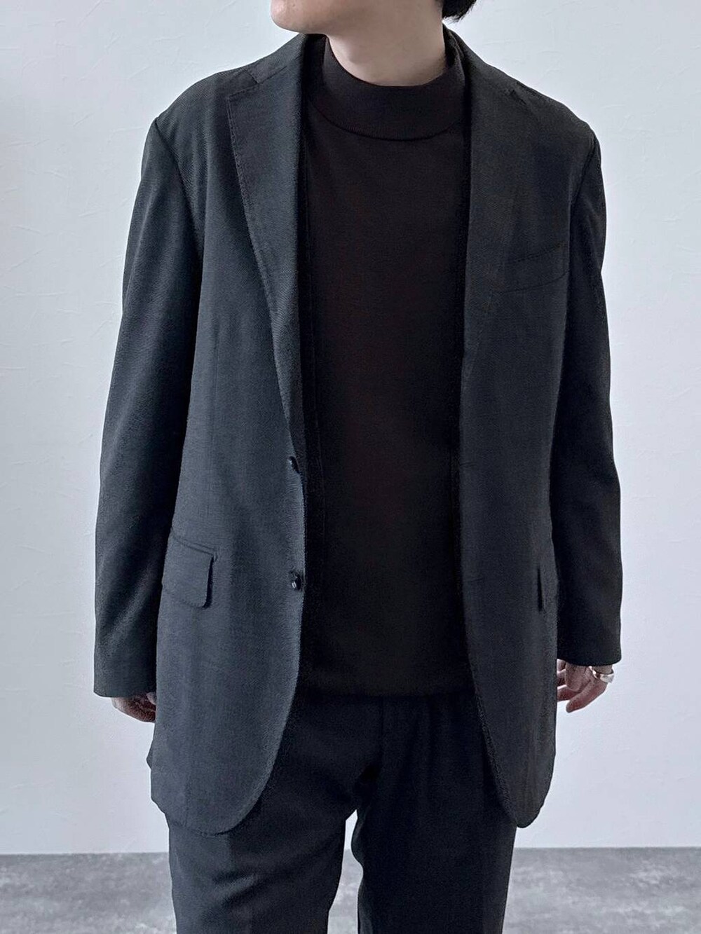 グレー系のテーラードジャケット、グレー系のスラックス、ブラウン系のニット/セーターを着用したメンズの秋コーディネートの4枚目の写真