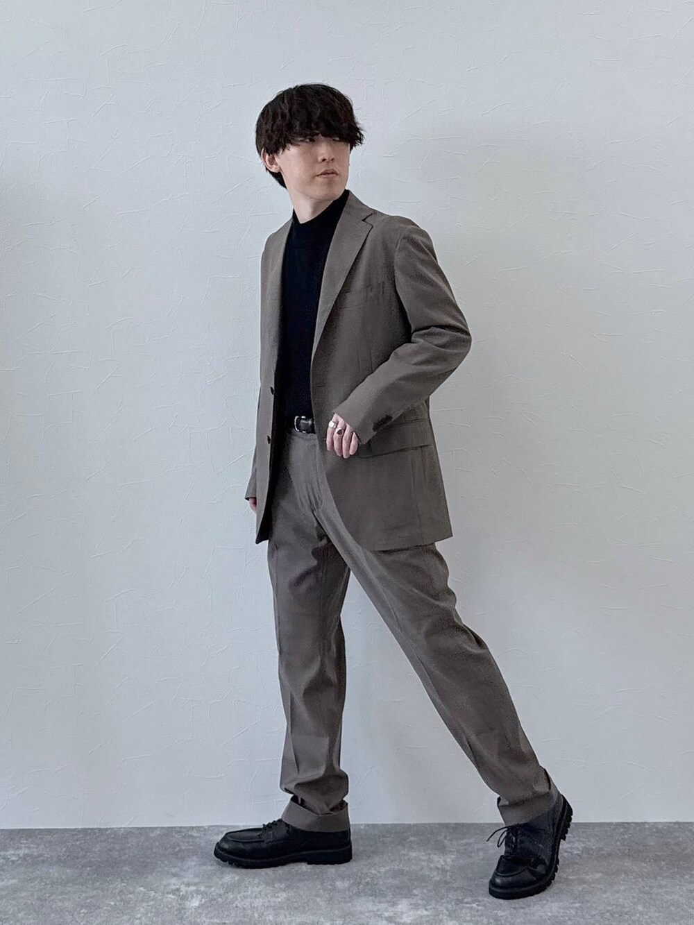 ブラウン系のテーラードジャケット、ブラウン系のスラックス、ブラック系のニット/セーターを着用したメンズの秋コーディネートの2枚目の写真