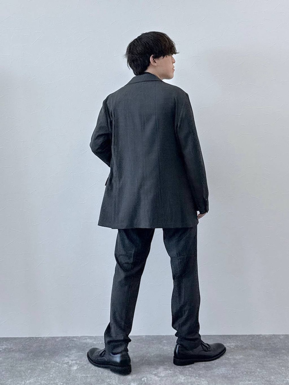 グレー系のテーラードジャケット、グレー系のスラックス、ブラウン系のニット/セーターを着用したメンズの秋コーディネートの3枚目の写真