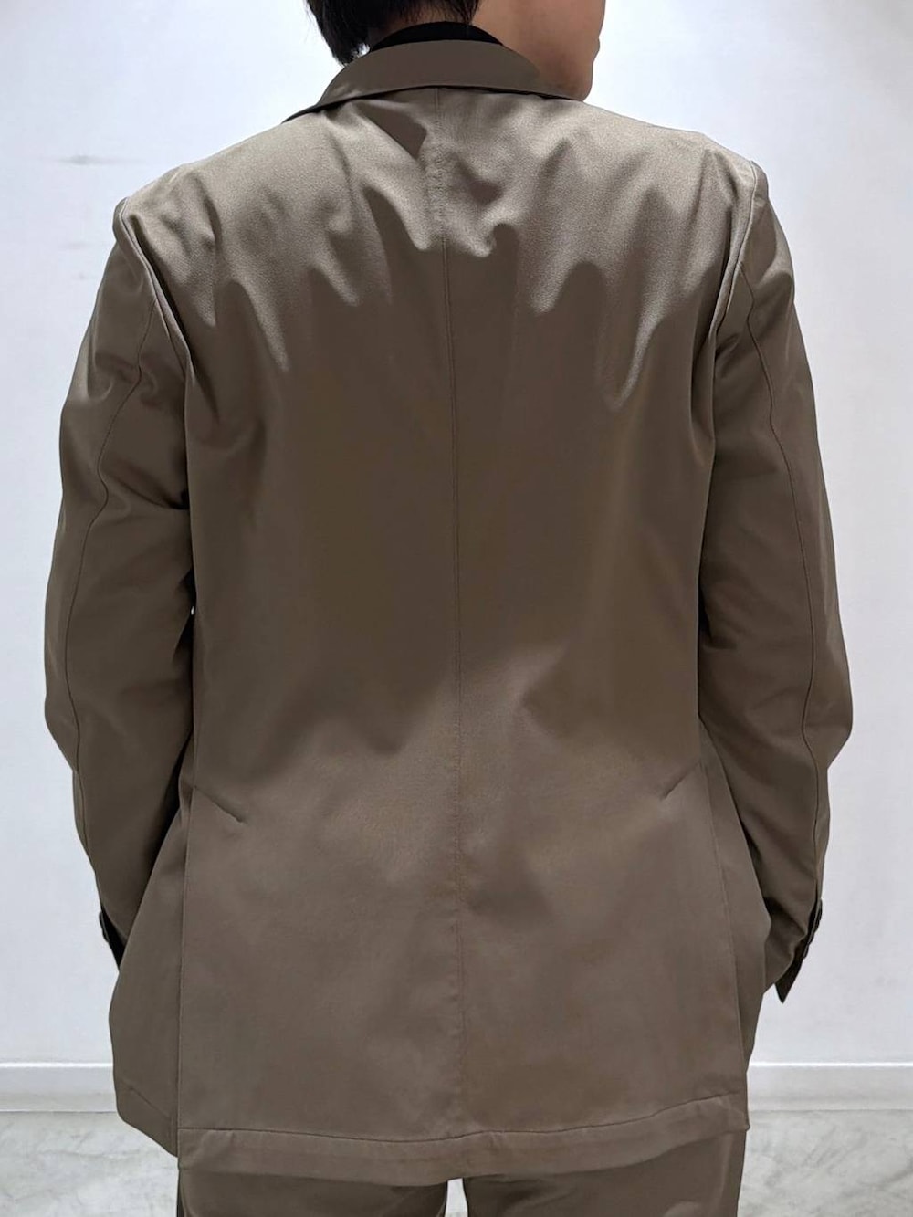 ブラック系のニット/セーター、ベージュ系のテーラードジャケット、ベージュ系のスラックスを着用したメンズの冬コーディネートの5枚目の写真