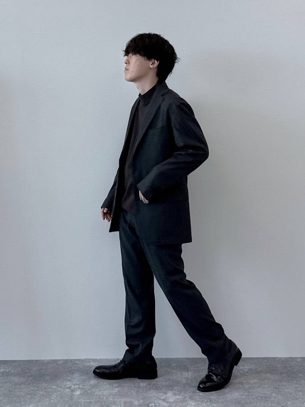 グレー系のテーラードジャケット、グレー系のスラックス、ブラウン系のニット/セーターを着用したメンズの秋コーディネートの2枚目の写真