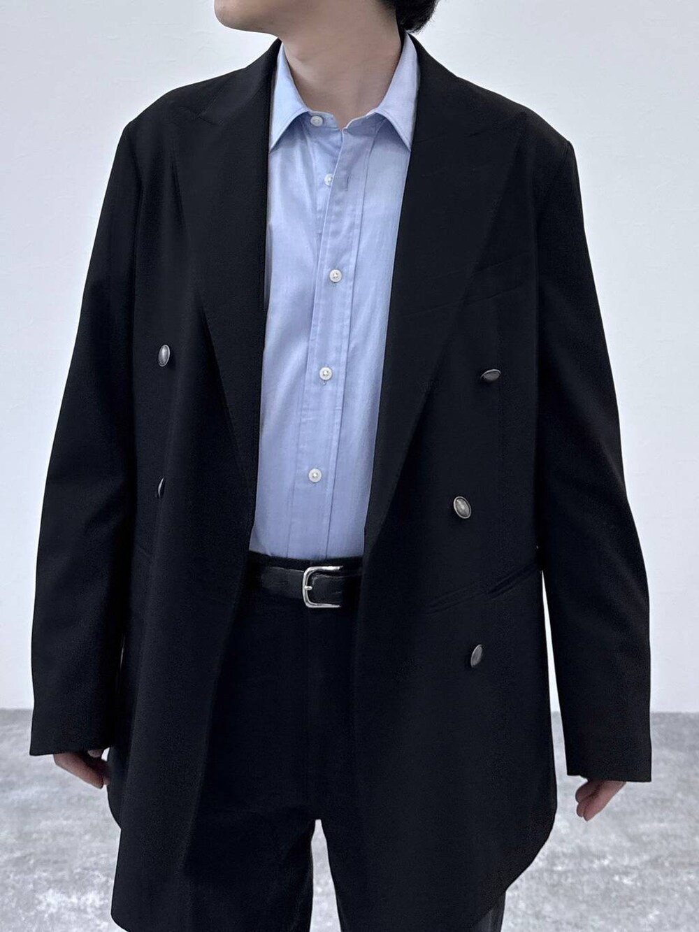 ブラック系のテーラードジャケット、ブラック系のデニムパンツ、ブルー系のシャツ/ブラウスを着用したメンズの秋コーディネートの4枚目の写真