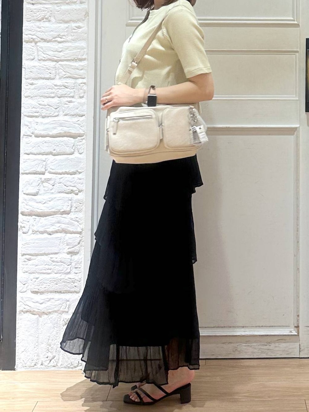 ホワイト系のタンクトップ、ブラック系のサンダル、ブラック系のスカートを着用したレディースの夏コーディネートの3枚目の写真