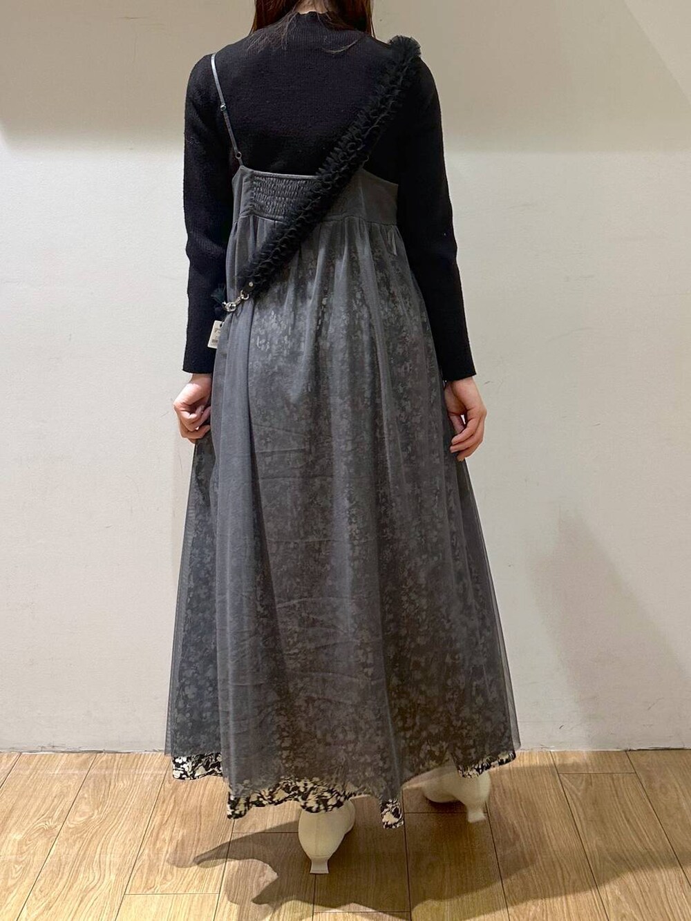 グレー系のワンピース、ホワイト系のブーツ、ブラック系のニット/セーターを着用したレディースの冬コーディネートの3枚目の写真