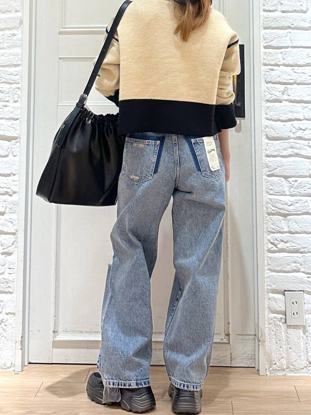 ブラック系のショルダーバッグ、ベージュ系のニット/セーター、ブルー系のデニムパンツを着用したレディースの冬コーディネートの4枚目の写真