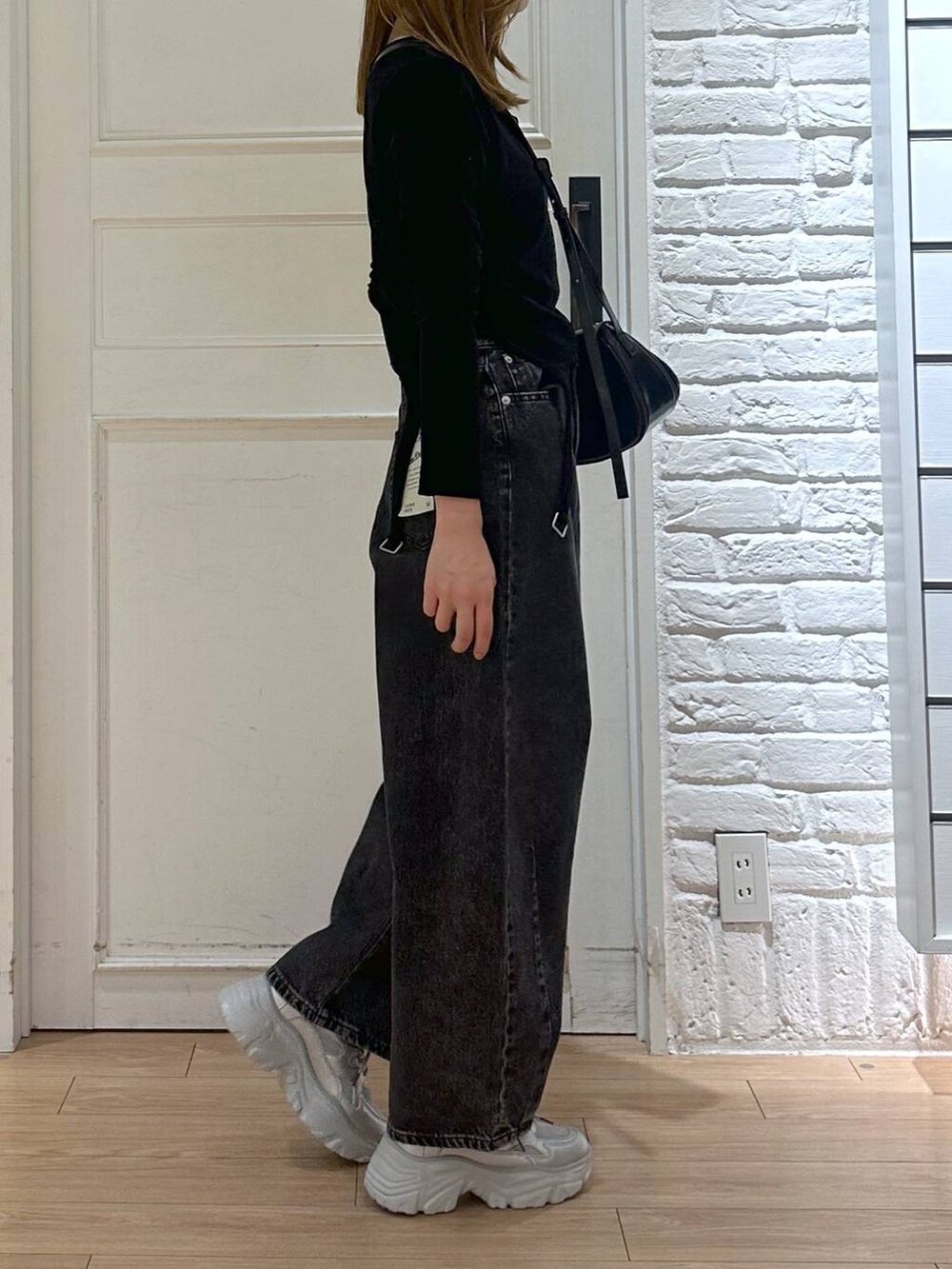 ブラック系のデニムパンツ、ブラック系のTシャツ/カットソー、シルバー系のスニーカーを着用したレディースの秋コーディネートの2枚目の写真