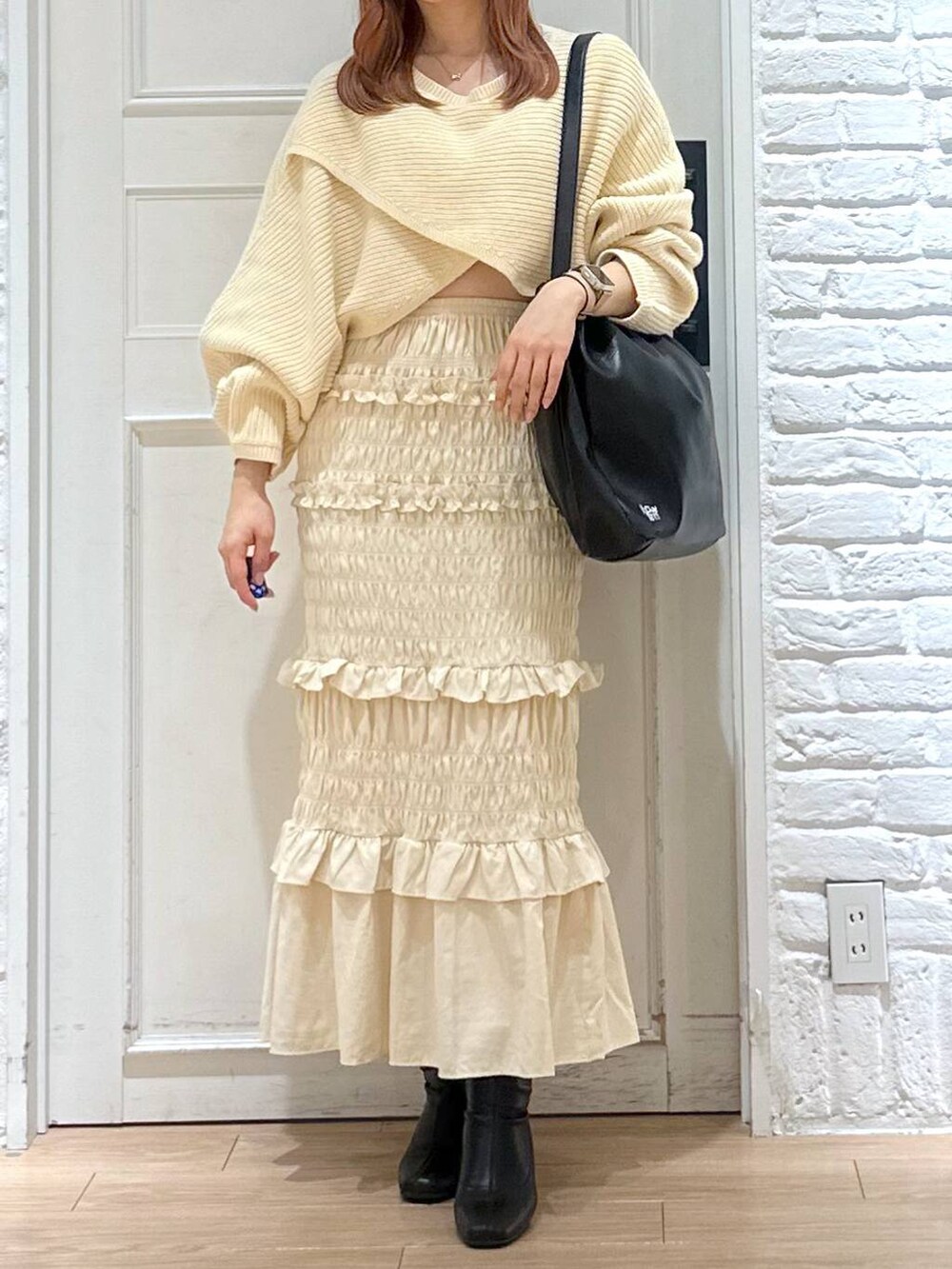 ホワイト系のニット/セーター、ブラック系のブーツ、ブラック系のショルダーバッグを着用したレディースの秋コーディネートの2枚目の写真