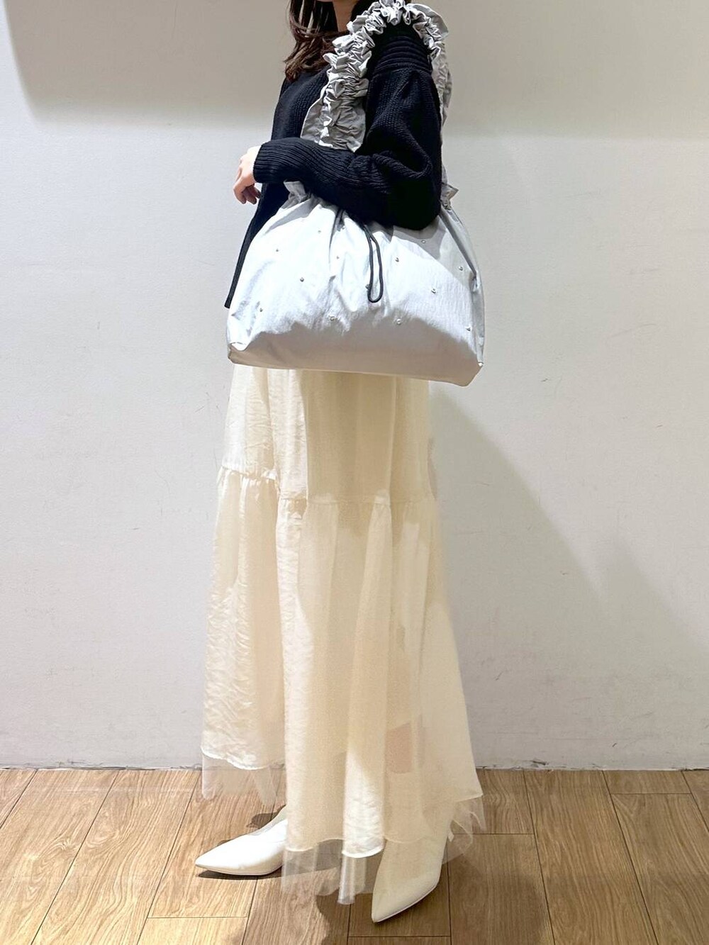 ホワイト系のブーツ、ホワイト系のスカート、グレー系のトートバッグを着用したレディースの冬コーディネートの2枚目の写真