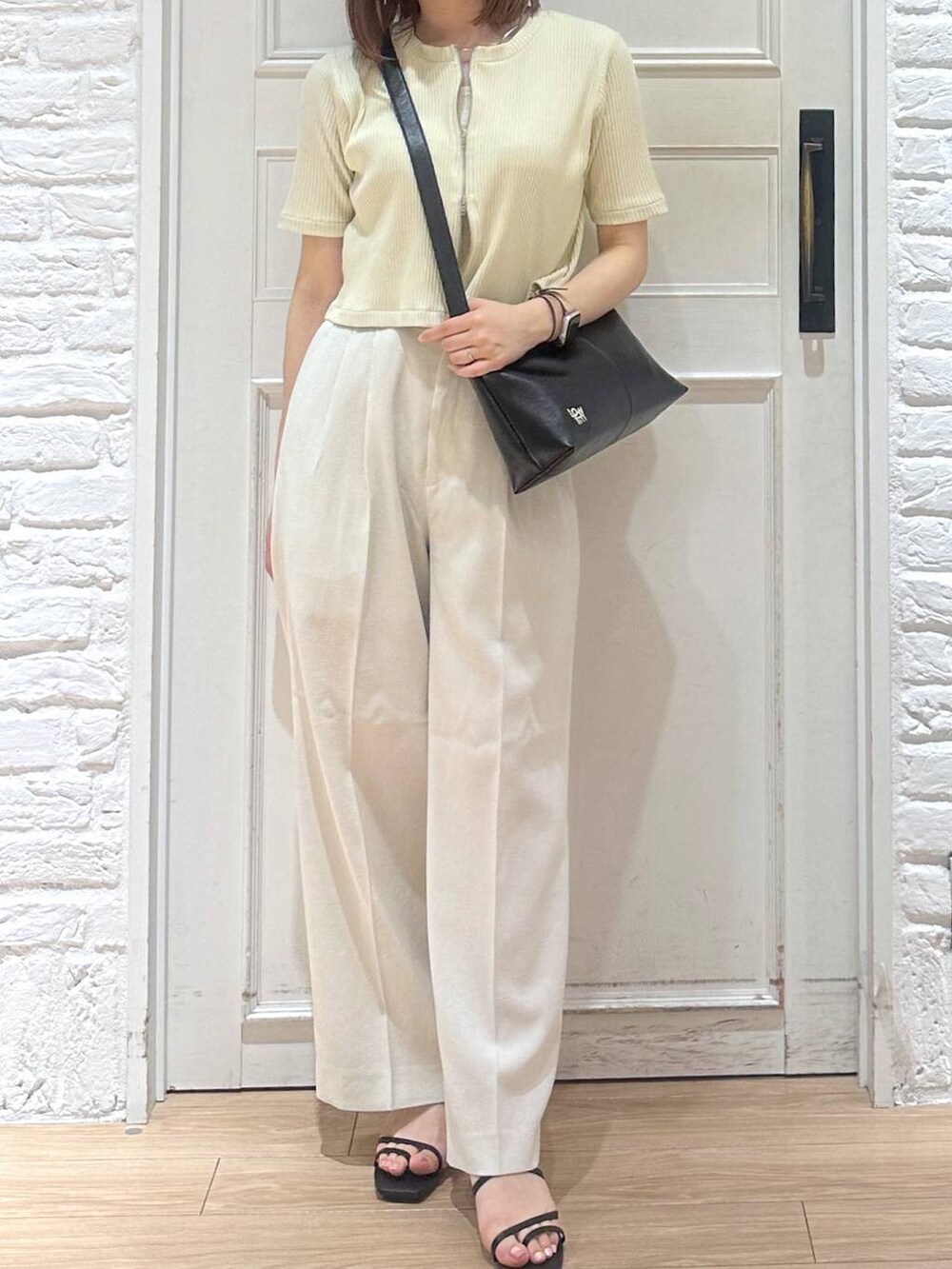 ホワイト系のスラックス、ホワイト系のタンクトップ、ブラック系のサンダルを着用したレディースの夏コーディネートの2枚目の写真