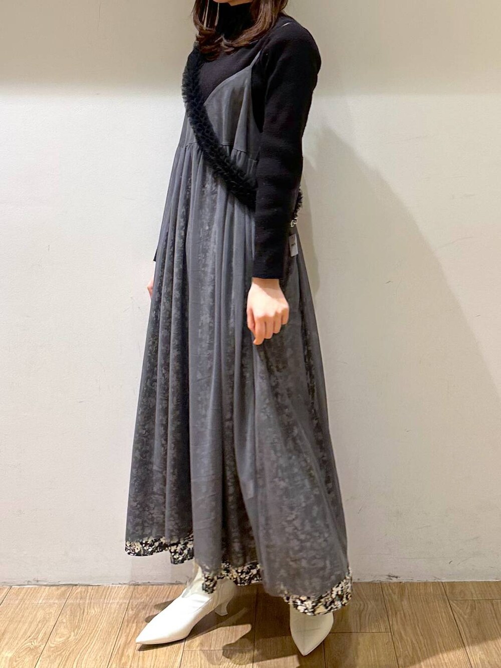 グレー系のワンピース、ホワイト系のブーツ、ブラック系のニット/セーターを着用したレディースの冬コーディネートの2枚目の写真