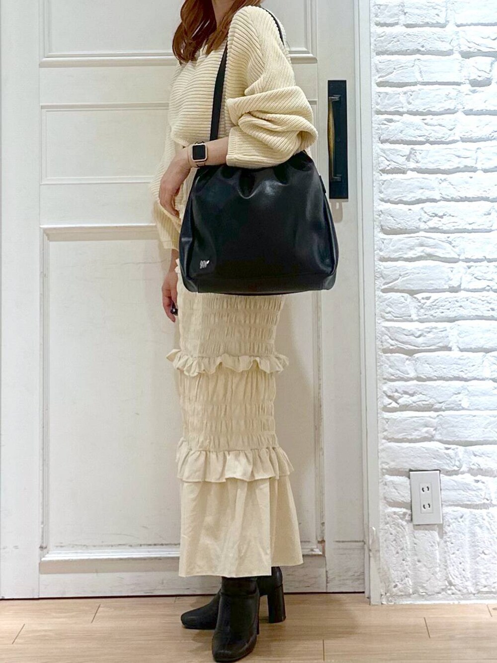 ホワイト系のニット/セーター、ブラック系のブーツ、ブラック系のショルダーバッグを着用したレディースの秋コーディネートの5枚目の写真