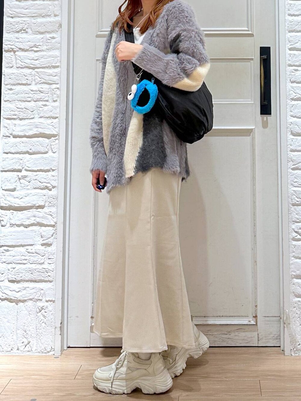 ホワイト系のスカート、ホワイト系のカーディガン/ボレロ、ホワイト系のスニーカーを着用したレディースの秋コーディネートの2枚目の写真