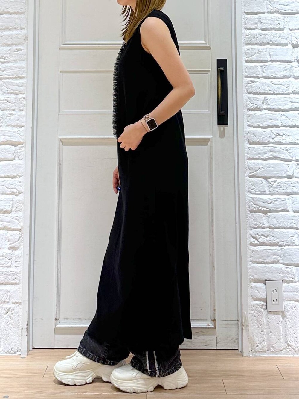 ブラック系のデニムパンツ、ブラック系のワンピース、ホワイト系のスニーカーを着用したレディースの夏コーディネートの3枚目の写真