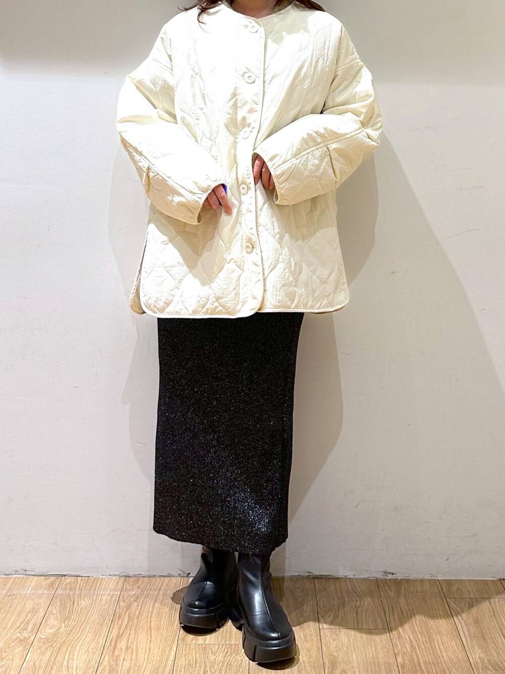 ホワイト系のブルゾン、ブラック系のブーツ、ブラック系のスカートを着用したレディースの冬コーディネートの2枚目の写真