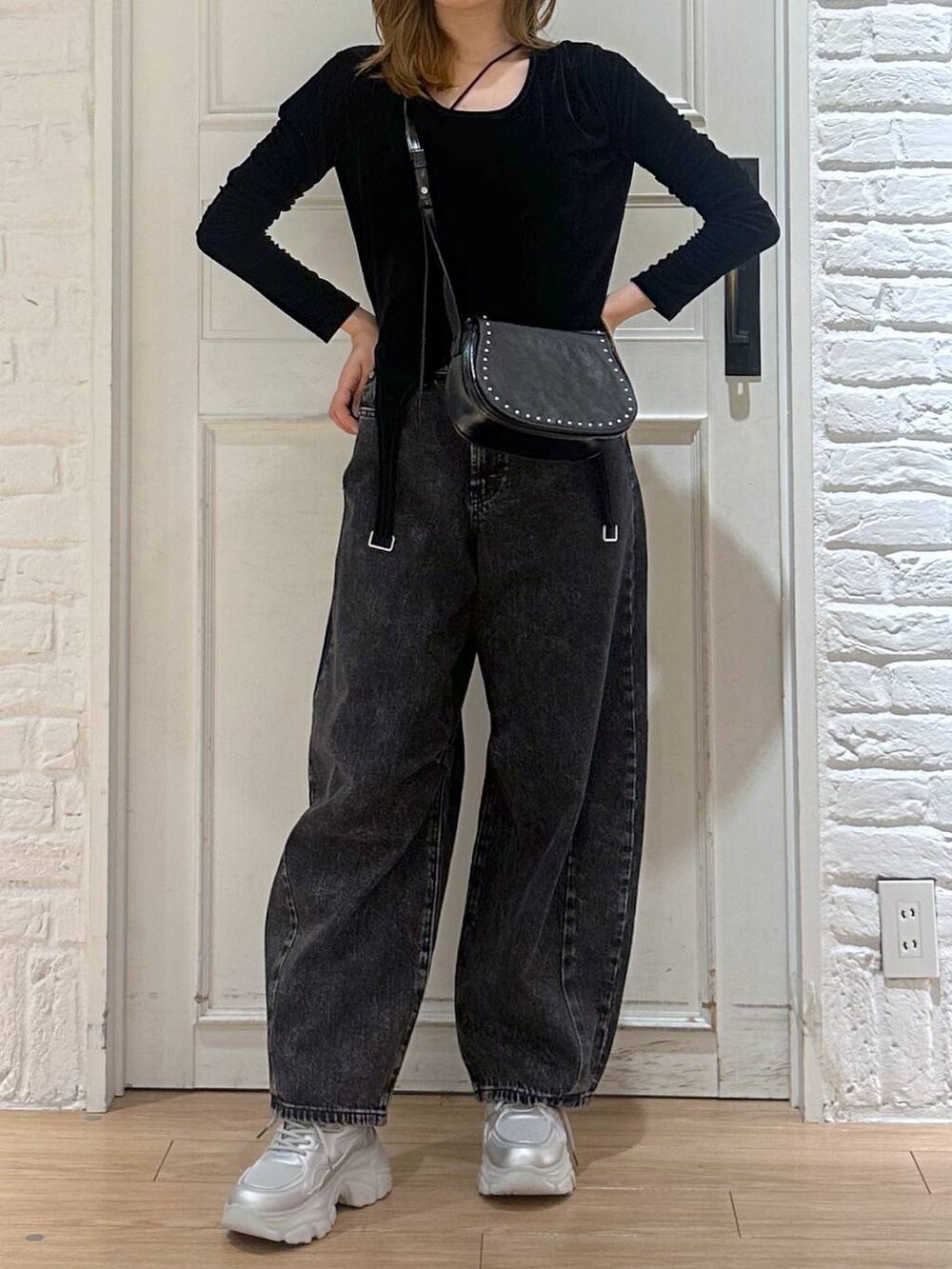 ブラック系のデニムパンツ、ブラック系のTシャツ/カットソー、シルバー系のスニーカーを着用したレディースの秋コーディネートの4枚目の写真