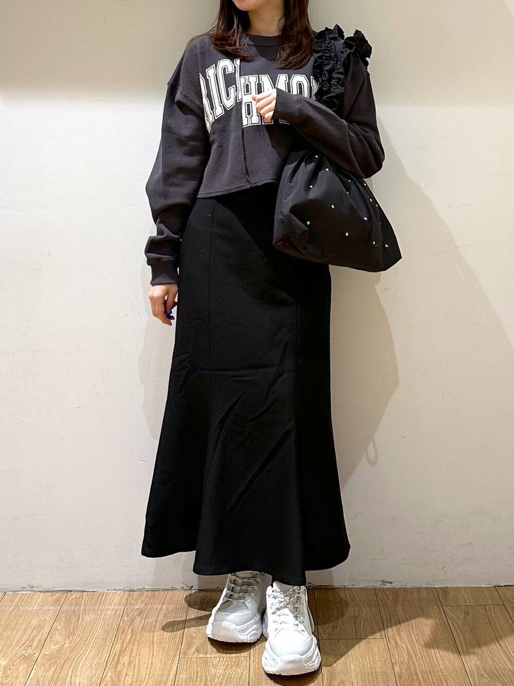 ブラック系のスカート、ブラック系のトートバッグ、ホワイト系のスニーカーを着用したレディースの冬コーディネートの4枚目の写真